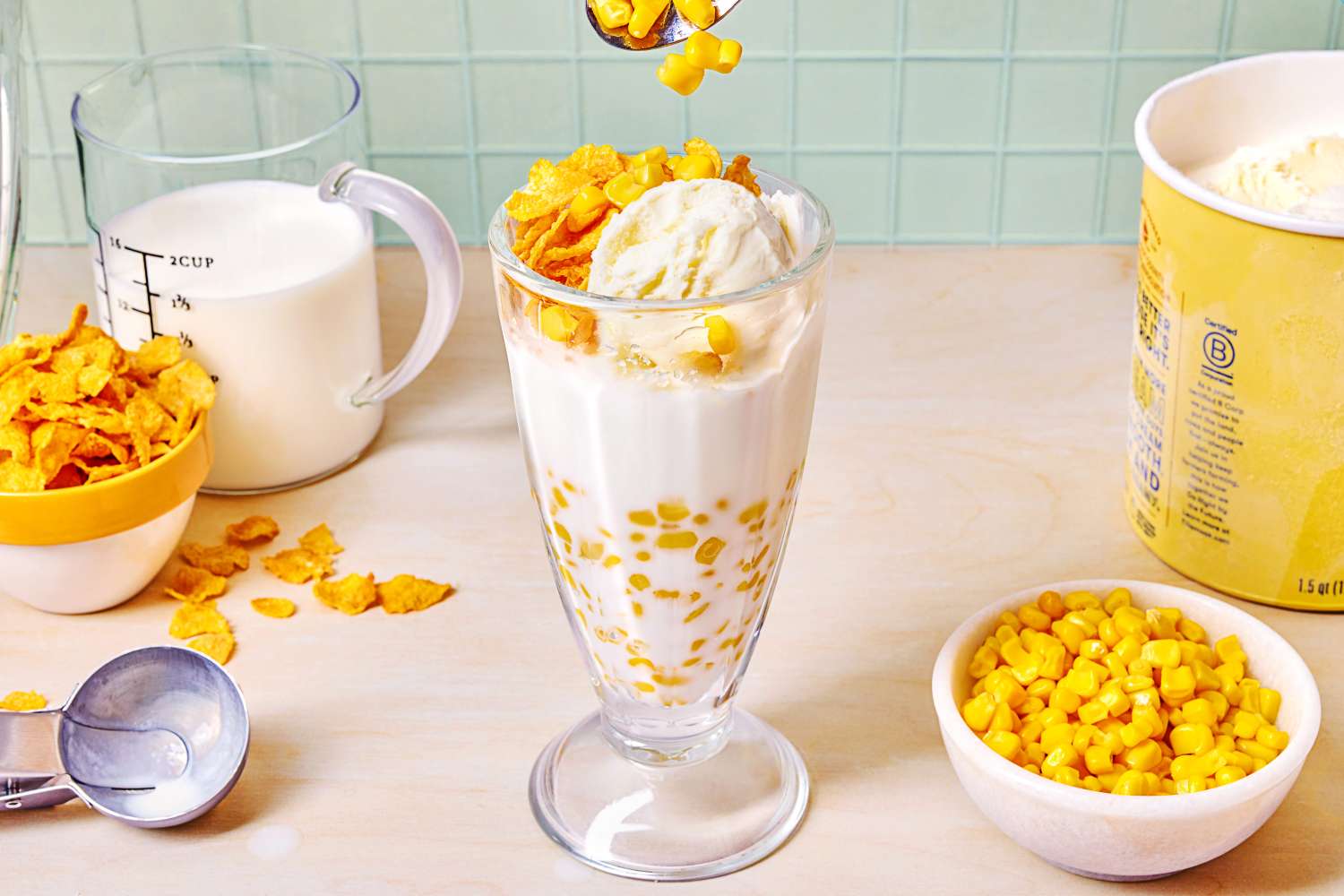 Maiz Con Hielo (Iced Corn with Milk), bowl of corn kernels, dish of corn flakes, pint of vanilla ice cream, measuring cup of cream/milk