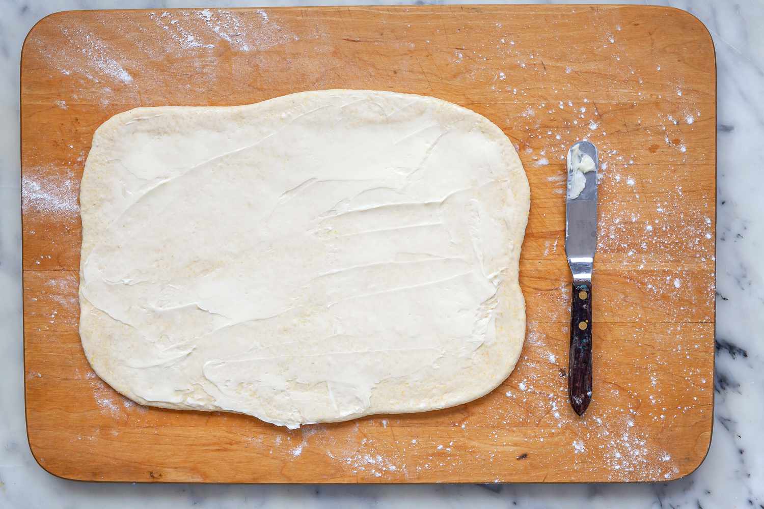 Dough rolled out and topped with butter to make Homemade Chicago-Style Deep Dish Pizza.