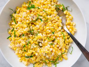 Bowl of cold corn salad with herbs served with a spoon