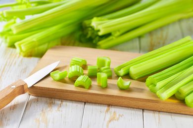 bunches of celery, a few chopped pieces on a cutting board