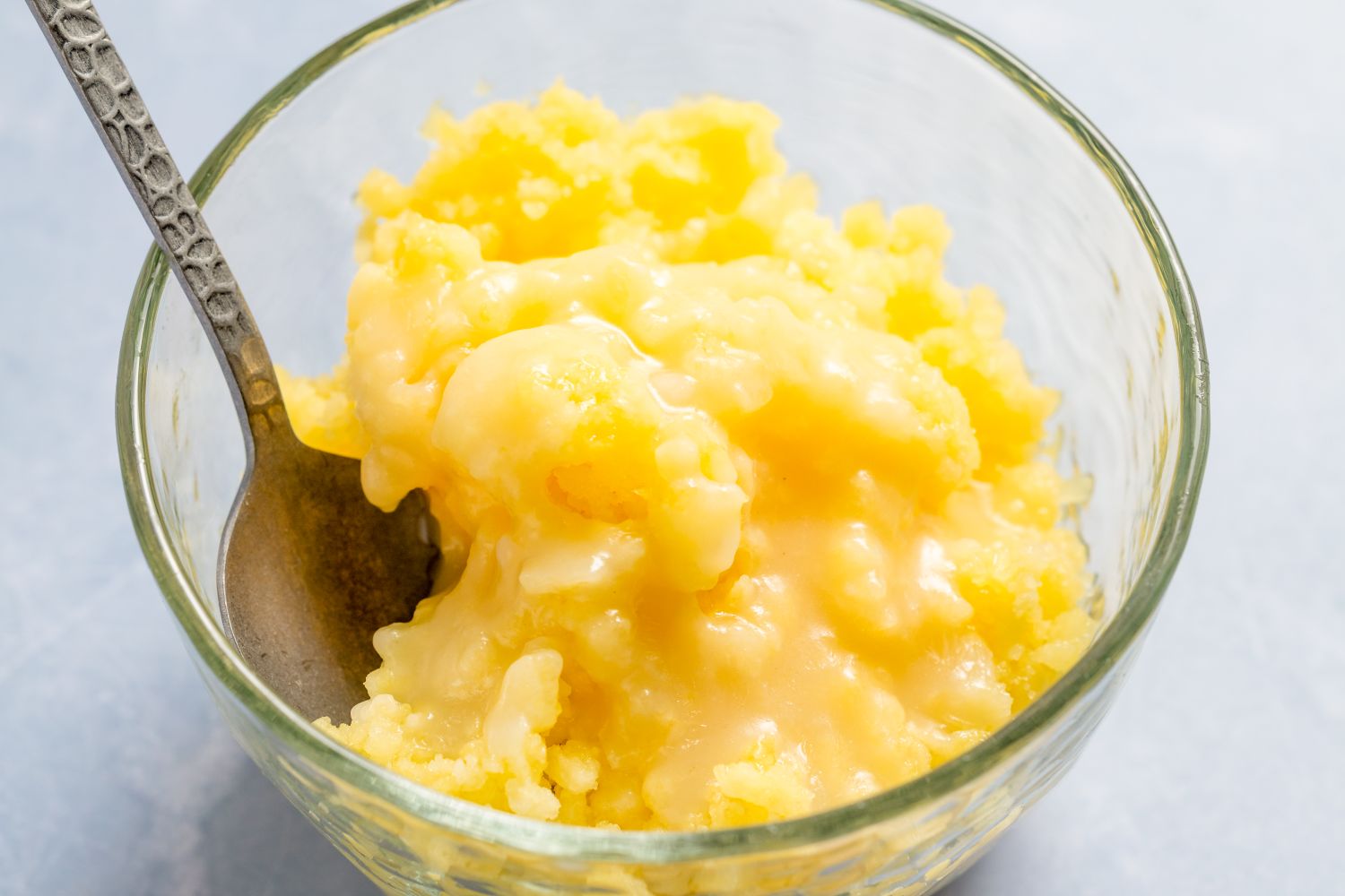 Pineapple coconut granita in a glass bowl with a spoon