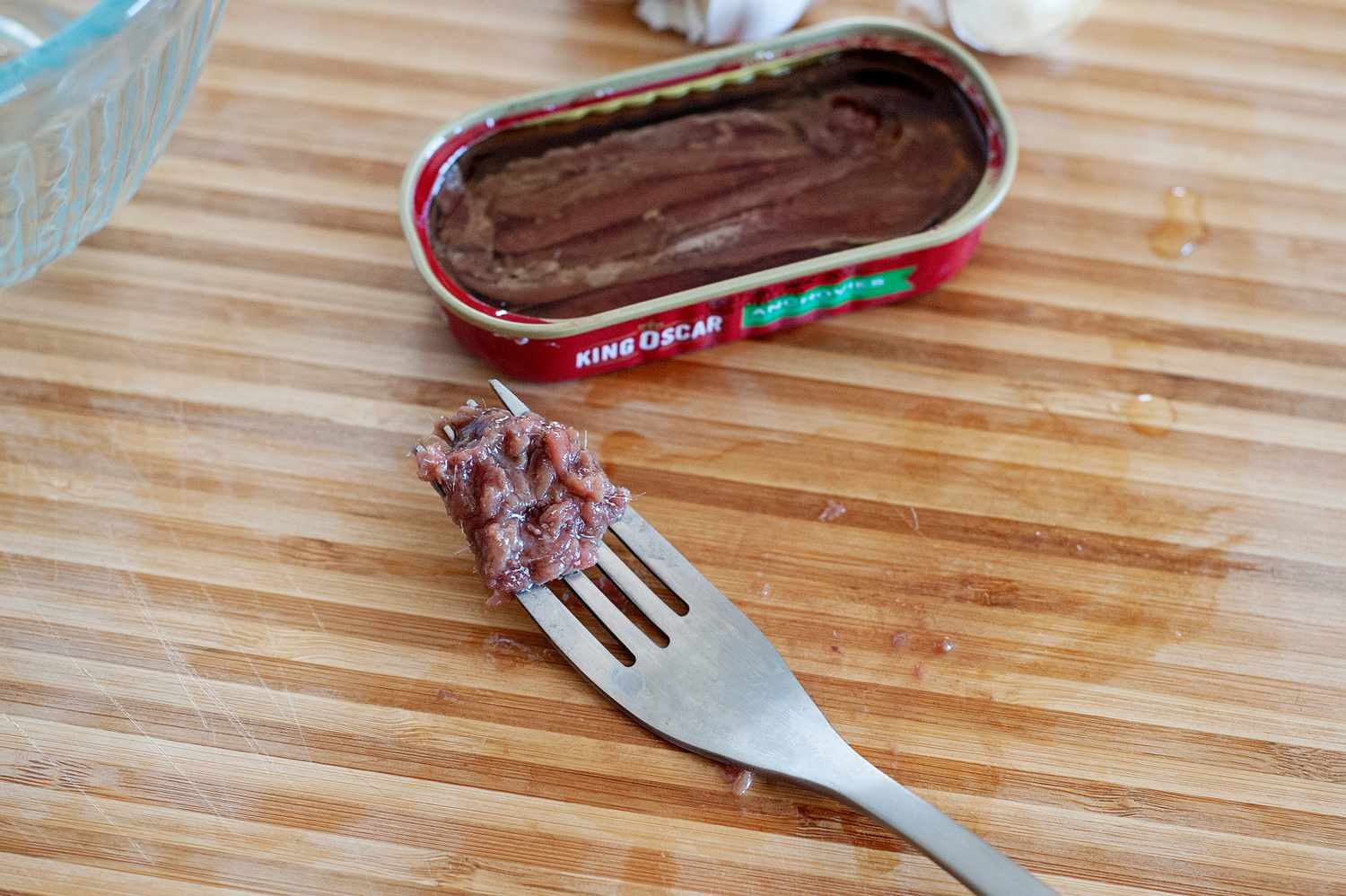Anchovies on a fork set next to the can.