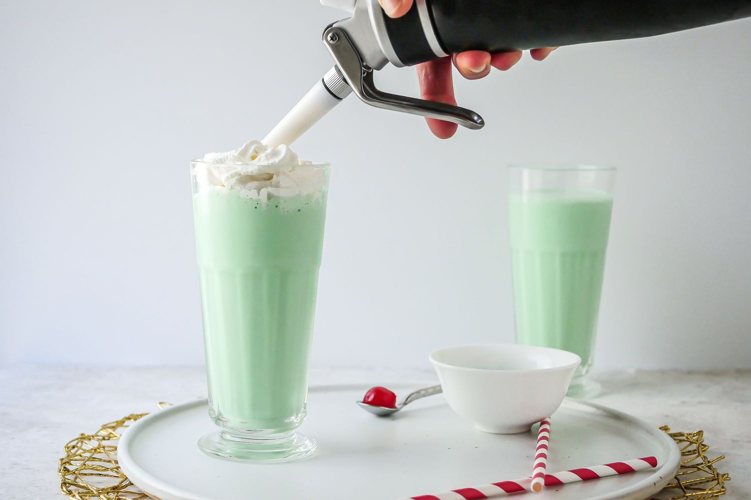 Topping a Copycat McDonald’s Shamrock Shake with whipped cream.