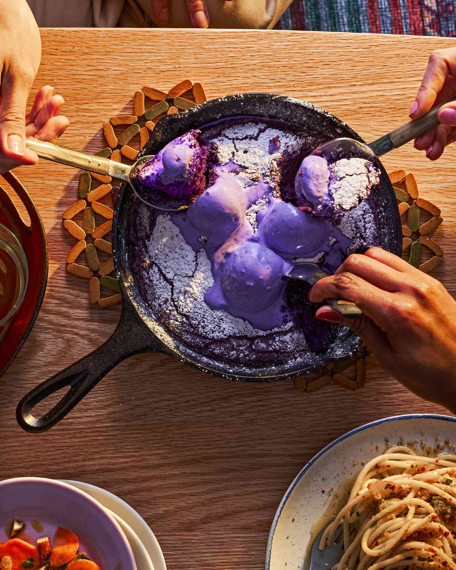 An ube skillet cookie on a coffee table, spoons digging in
