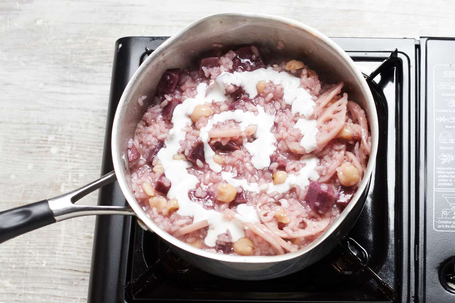Adding coconut milk to a pot of coconut rice pudding with lotus and sweet potato