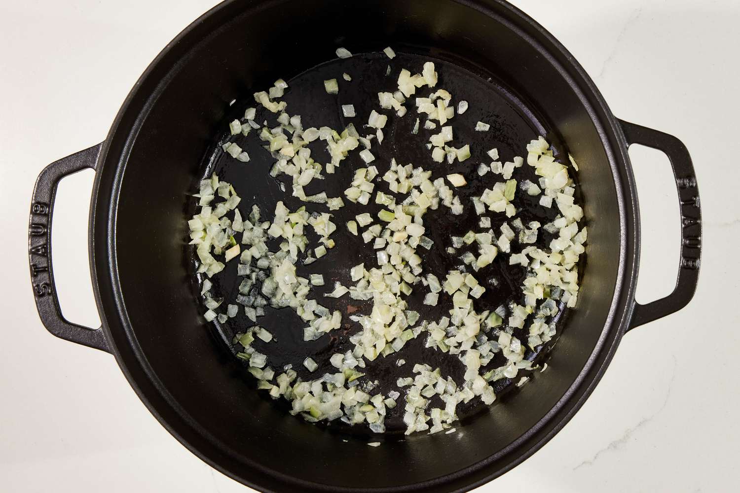 Diced onion cooking in a Dutch oven for copycat Panera broccoli cheddar soup recipe