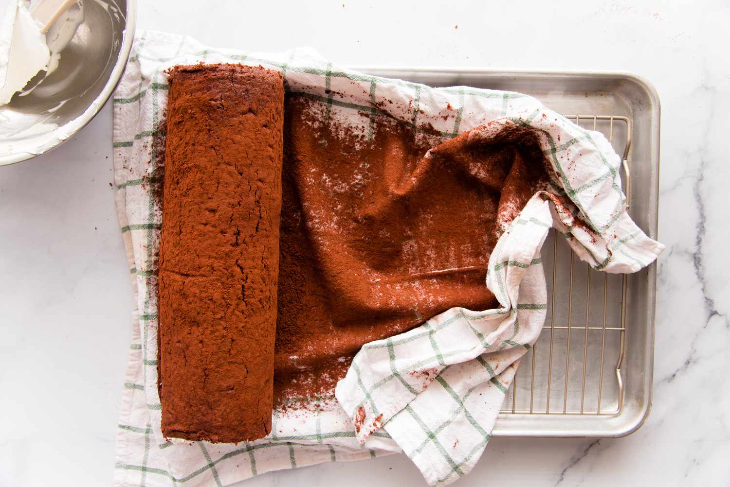 Cocoa covered tea towel under a chocolate swiss roll.