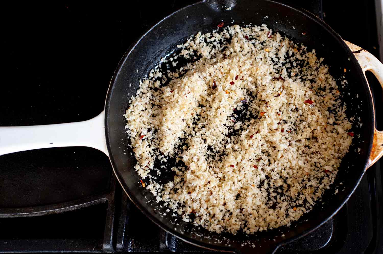 Adding breadcrumbs to skillet for a roasted cabbage steaks recipe.