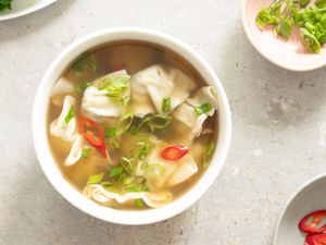 wanton soup next to a small bowl of sliced scallions
