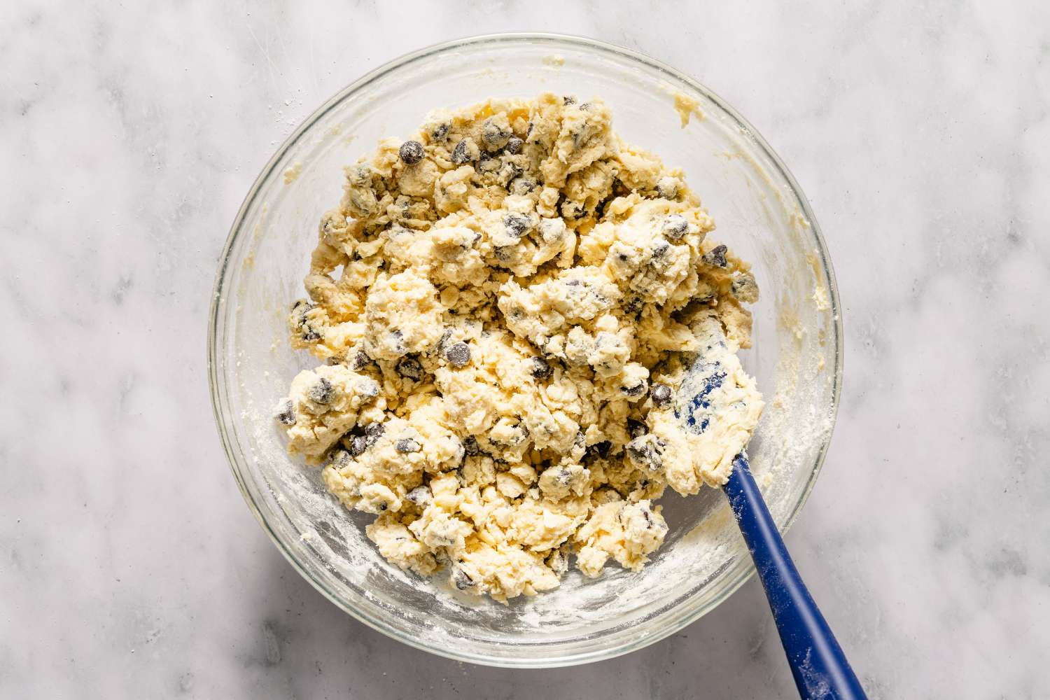 A bowl of chocolate chip scone dough with a spatula on a marble surface for Chocolate Chip Scones recipe