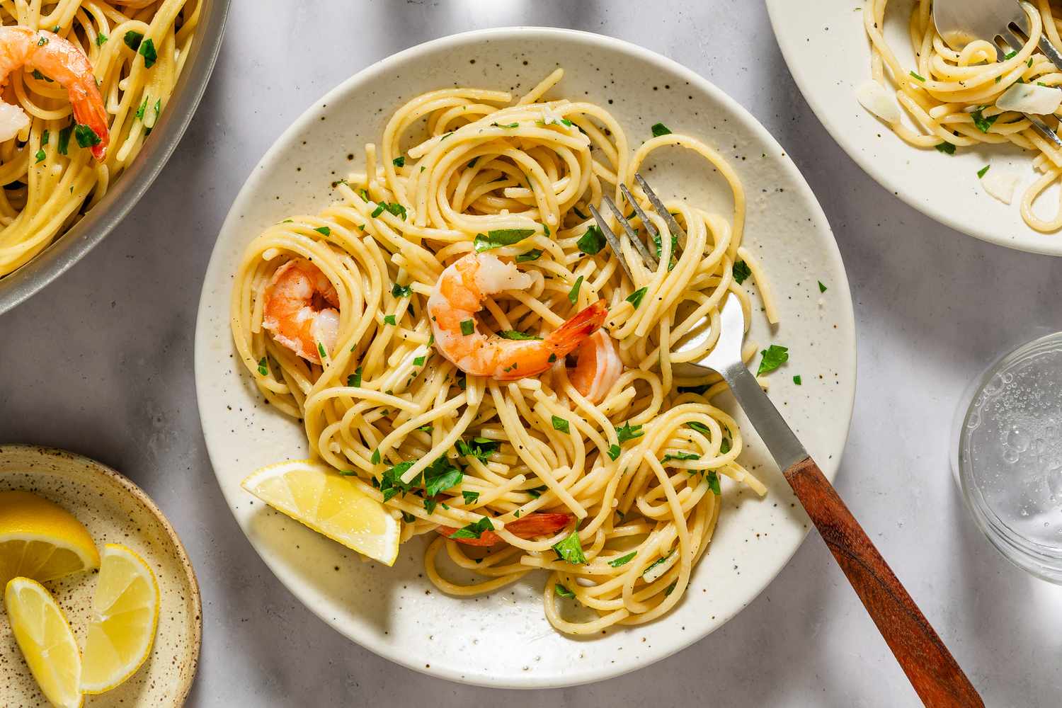 Garlic butter shrimp pasta served in a bowl with lemon wedges and parsley garnish