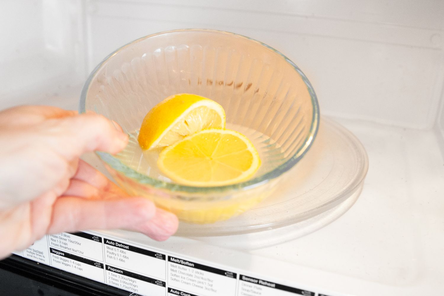 Bowl with Lemon Water and a Halved Lemon Placed into a Microwave for How to Clean a Microwave