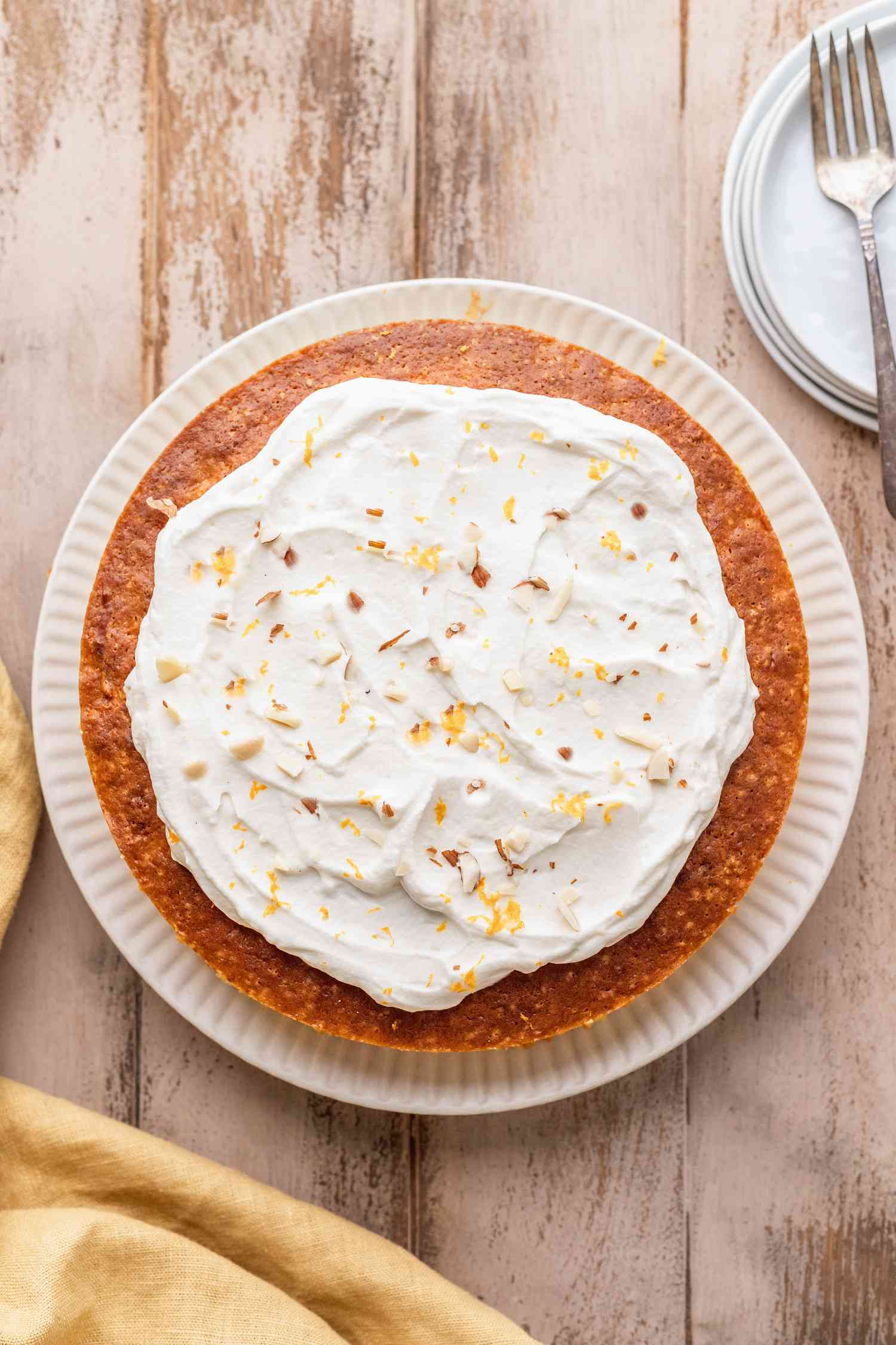 Clementine cake on essay with dessert plates on the side.