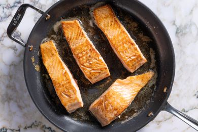 Salmon fillets getting pan fried skin side down