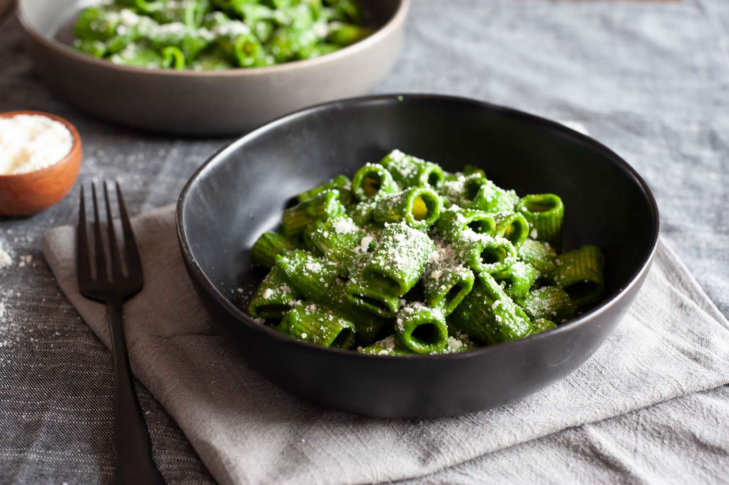 Swiss chard, lemon, and parmesan pasta heaped in a low bowl with a fork next to it.