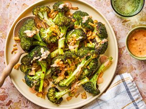 plate of Bang Bang Broccoli smothered with Bang Bang sauce and garnished with fried onions and a small dish of sauce on the side