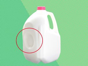 Plastic milk jug with an indentation highlighted by a red circle against a patterned green background