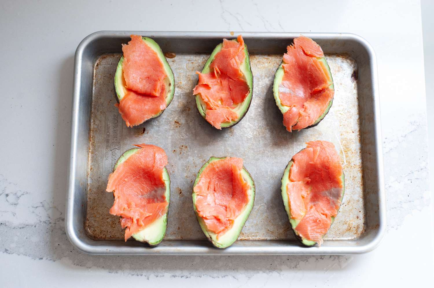 Avocados lined with lox on a sheet pan to make avocado baked eggs.