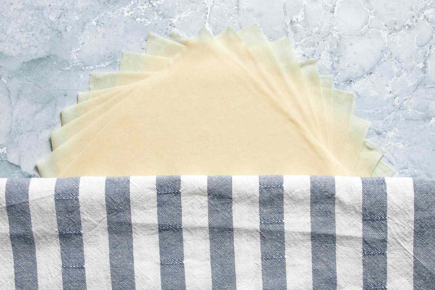 Egg Roll Wrappers on the Counter and Partially Covered With a Kitchen Towel