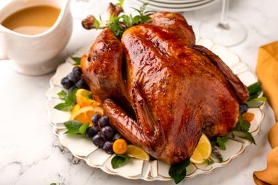 Roasted turkey garnished with fruits and greens served on a decorative platter