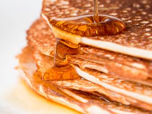 Stack of pancakes with syrup being poured over them
