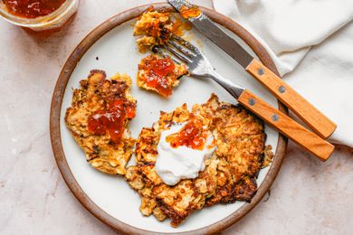 Overhead view of a plate of Matzo Brei Pancakes with a fork and knife on a pink marble countertop