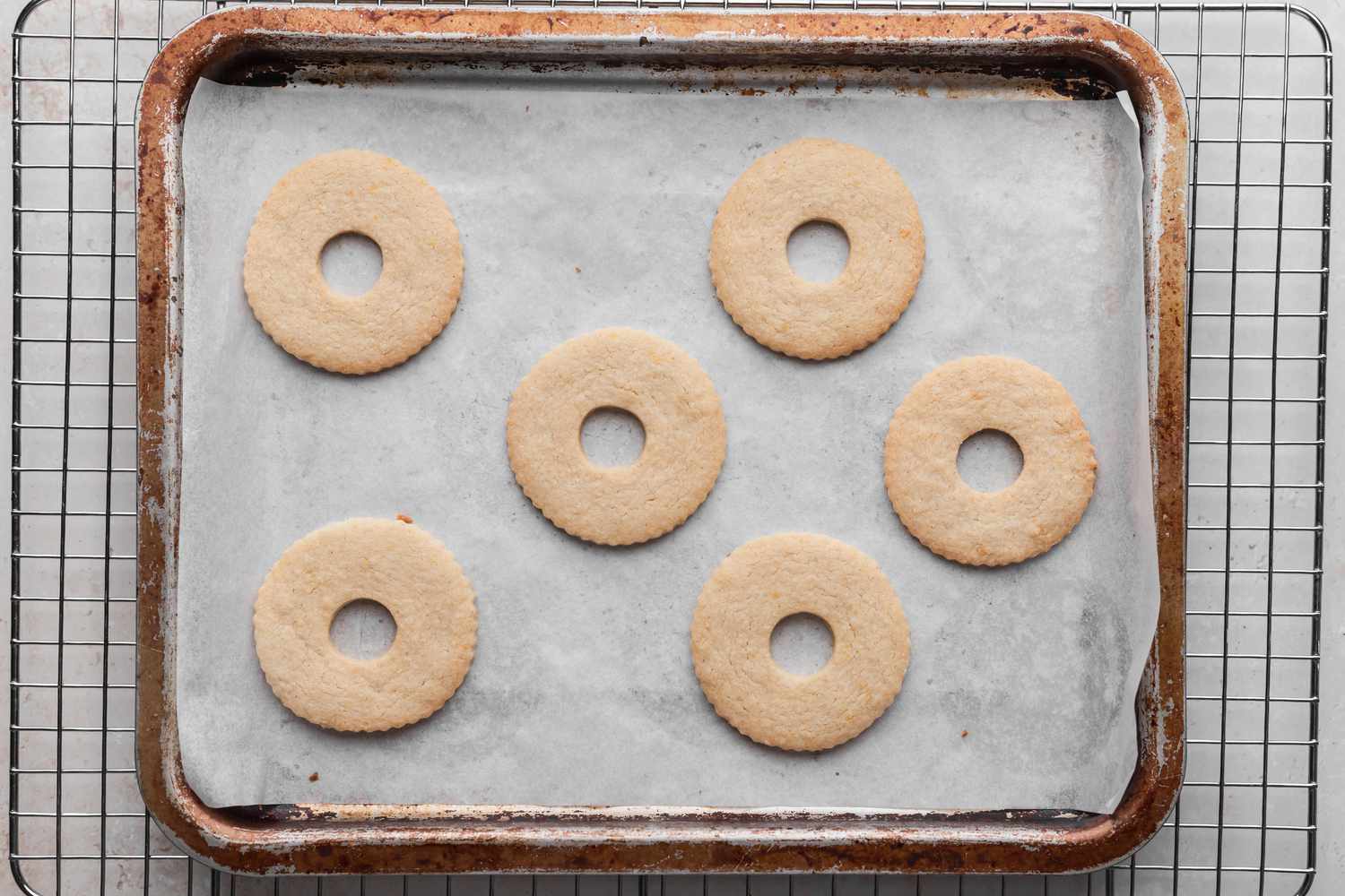 Linzer cookies on a baking sheet cooling on a rack..