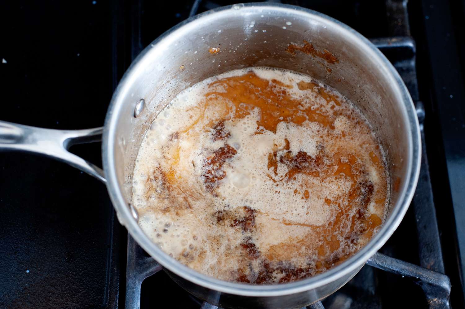 Adding milk to a saucepan to make butter pecan ice cream recipe.