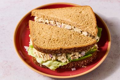 Tuna salad sandwich on whole grain bread, served on a red plate
