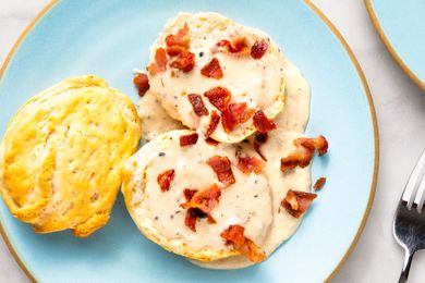 Biscuits topped with gravy and bacon pieces on a plate