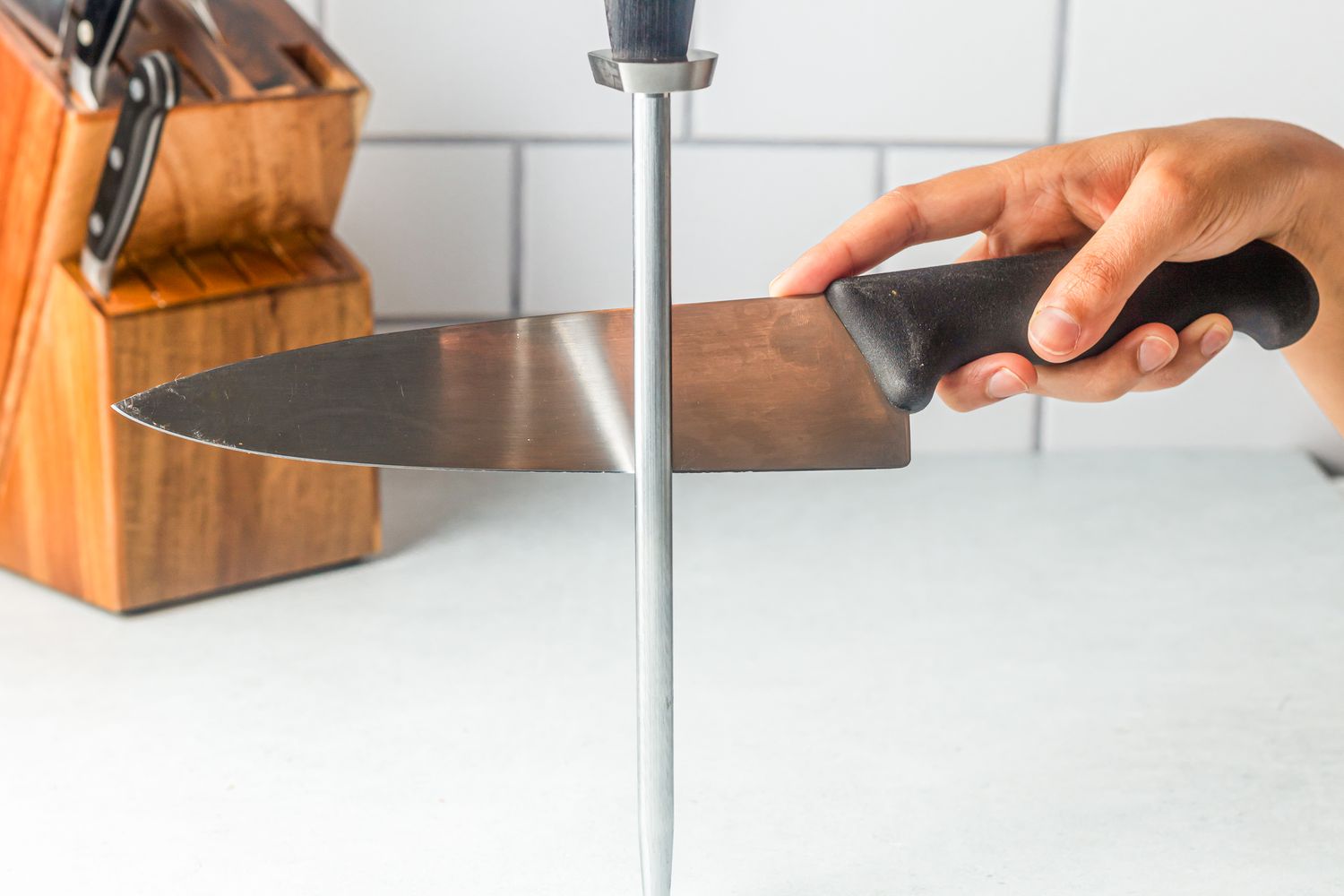 A hand honing a chef's knife with a honing steel