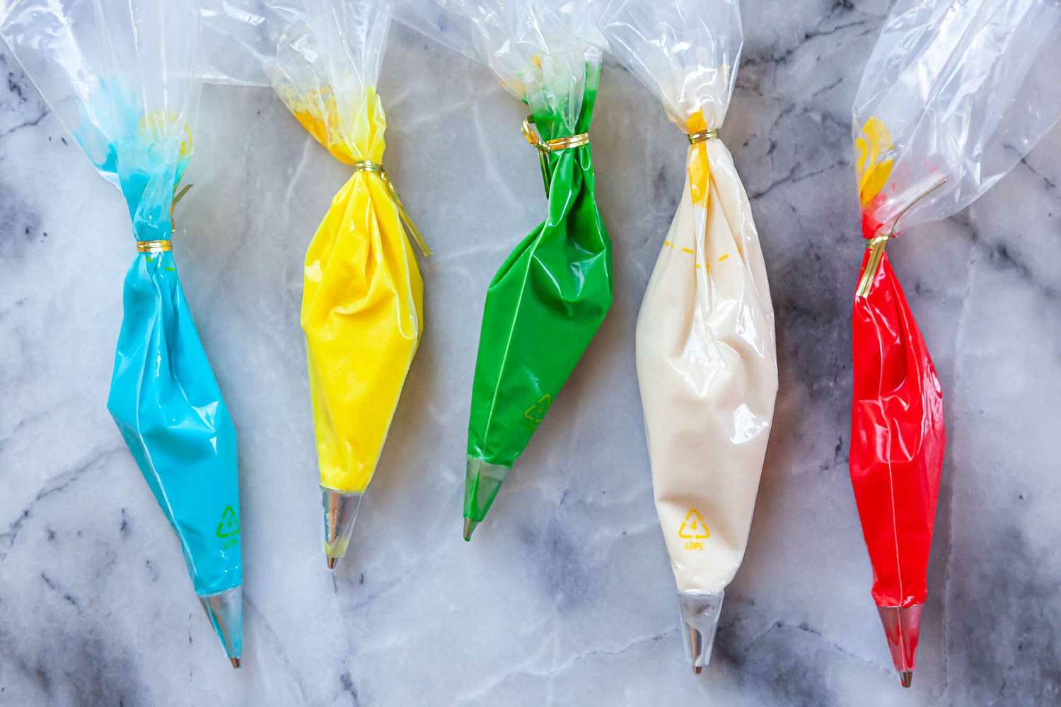 5 piping bags filled with different colors of Royal icing.