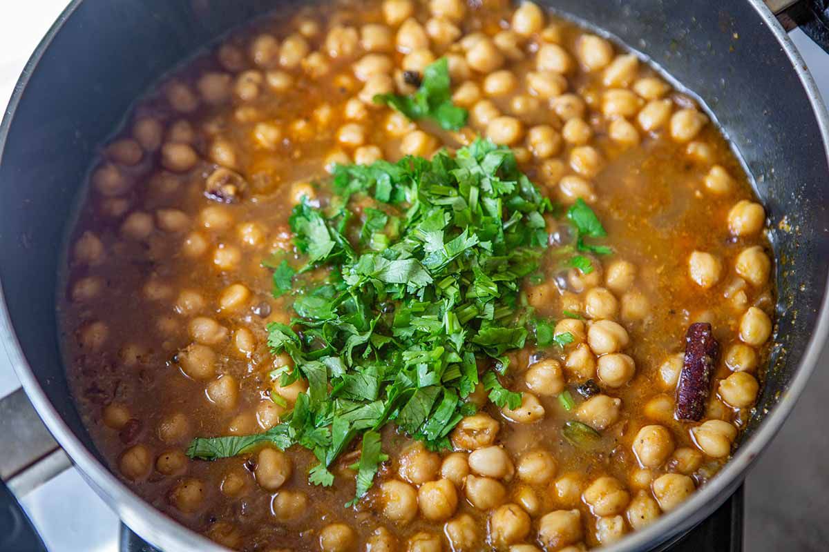 Easy Chana Masala Recipe - - chickpeas in spicy liquid with fresh, green herbs.