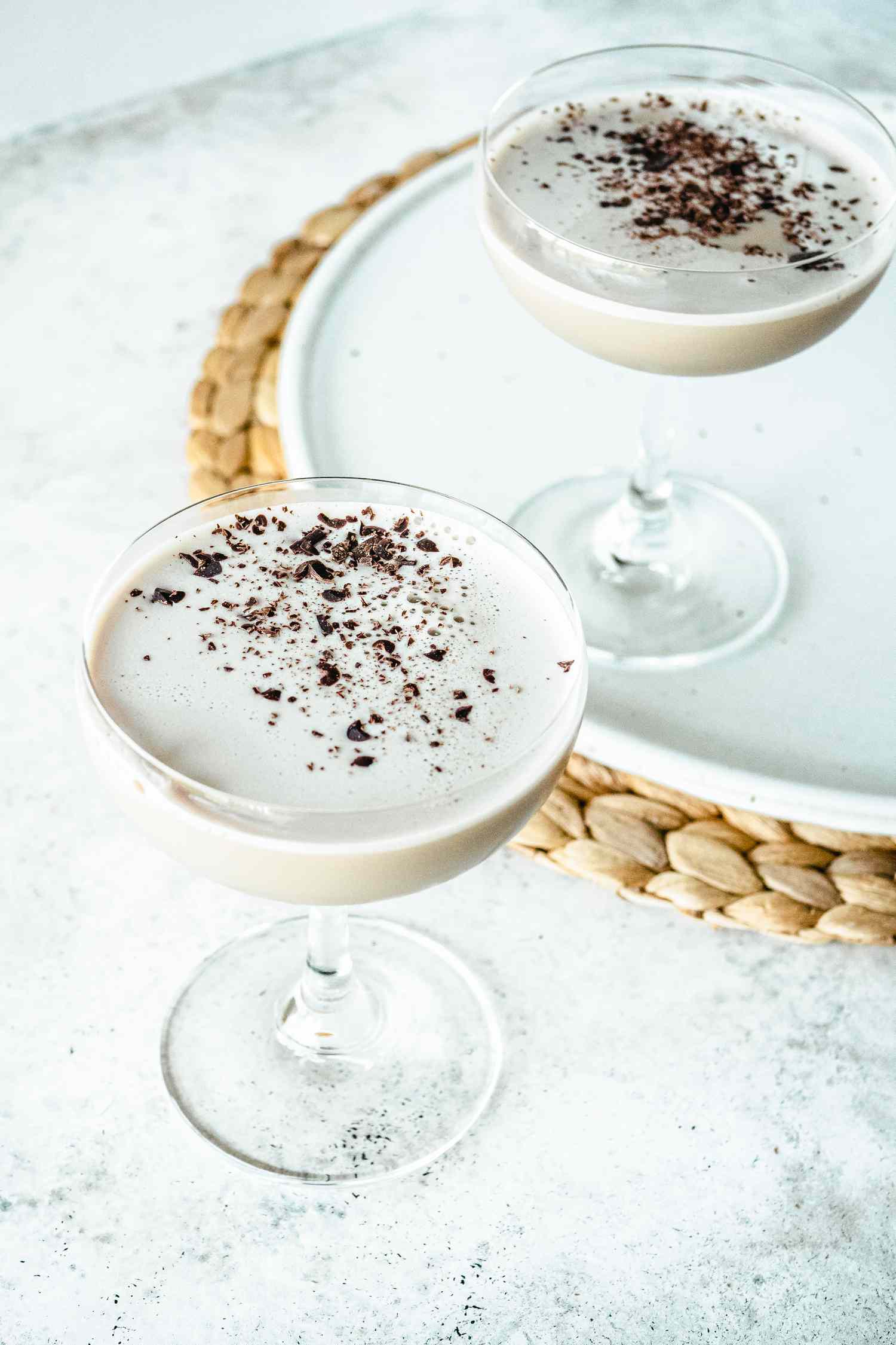 Creamy coffee cocktail in a stemmed glass with a second cocktail behind it on a tray.