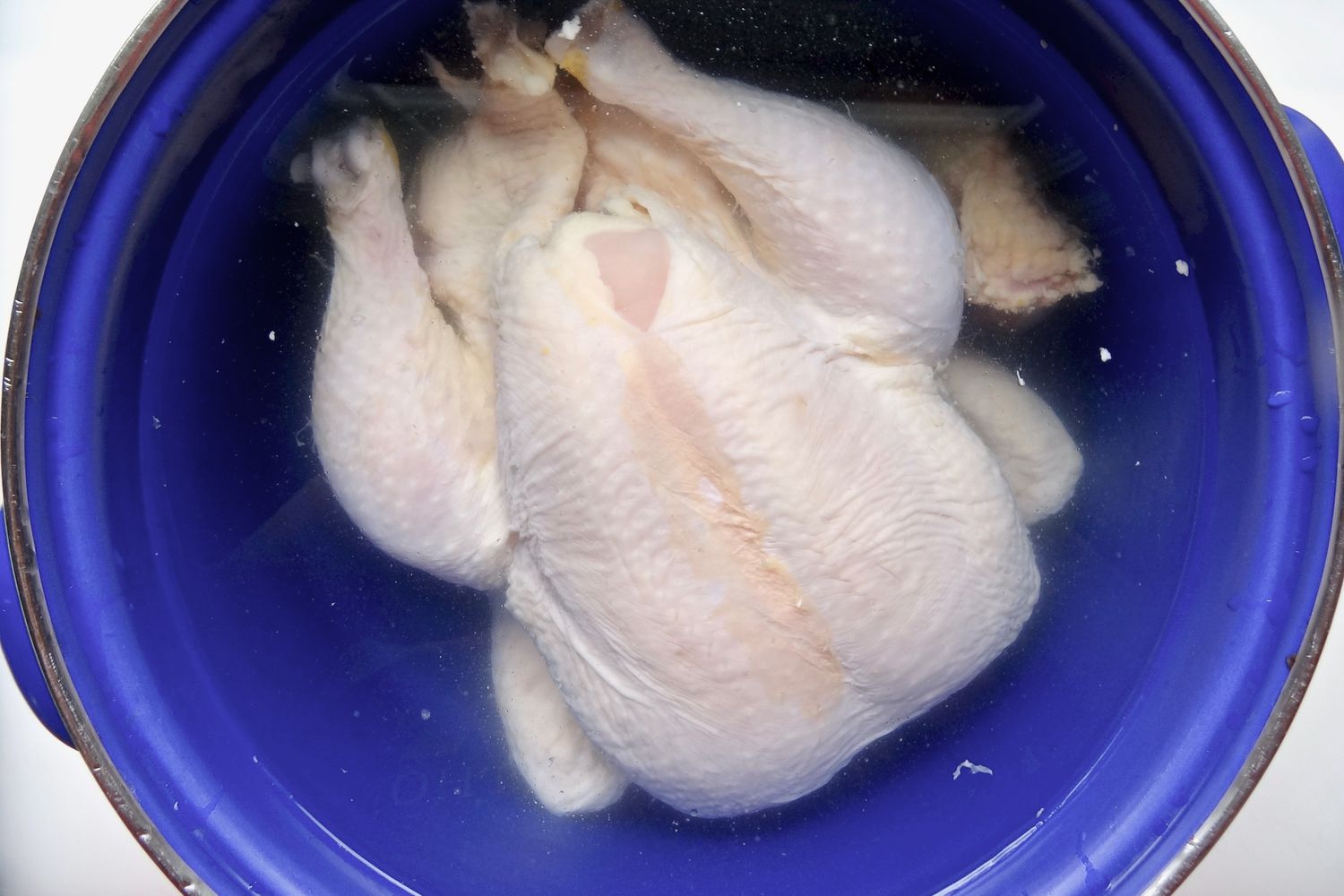 A pot with a whole chicken inside covered with water to make easy pork wontons in homemade chicken broth