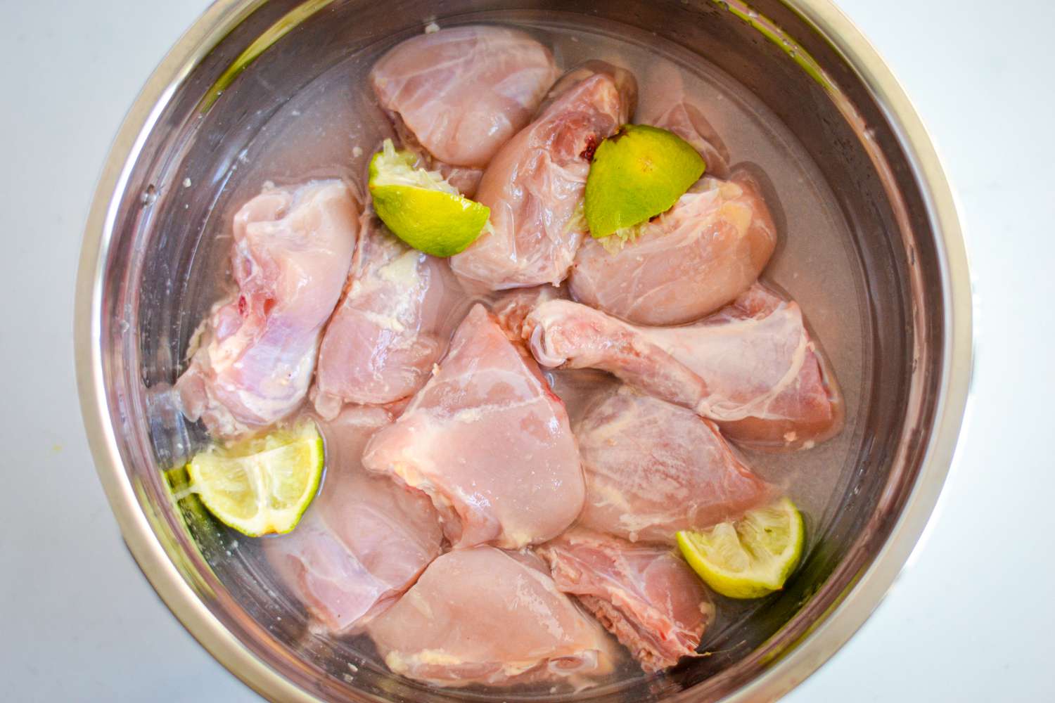 Uncooked Chicken Legg and Thigh in a Bowl with Lime Juice for Guyanese Chicken Curry