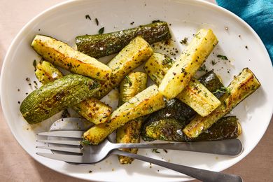 Roasted zucchini served on a white plate with utensils