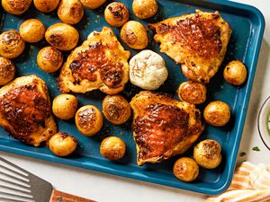 Overhead view of a baking sheet of roast chicken thighs and potatoes
