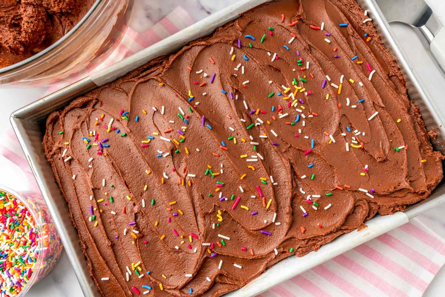 Tray of chocolate cake with frosting and sprinkles