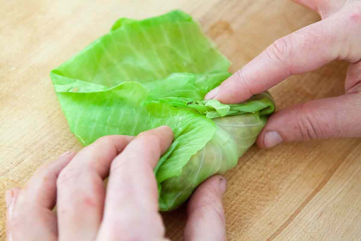 fold cabbage leave edges over pork stuffing to roll up for stuffed cabbage