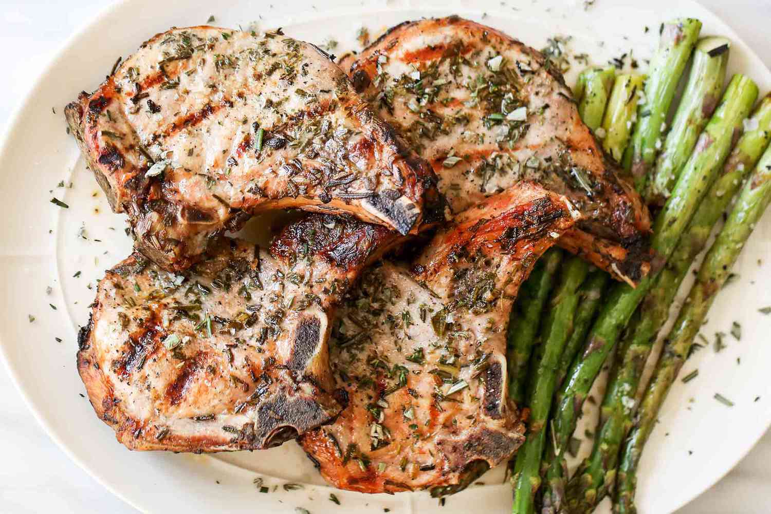 Grilled pork chops topped with herbs served with asparagus