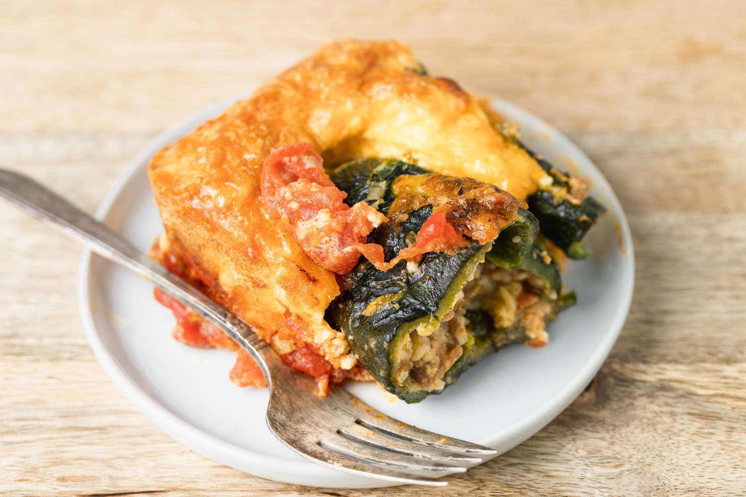 A white plate with chile relleno casserole and a fork.