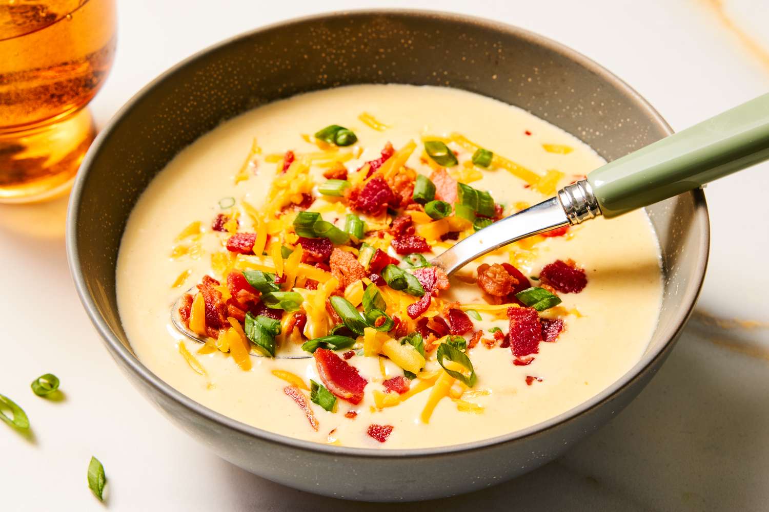 Bowl of potato soup topped with cheese bacon and green onions