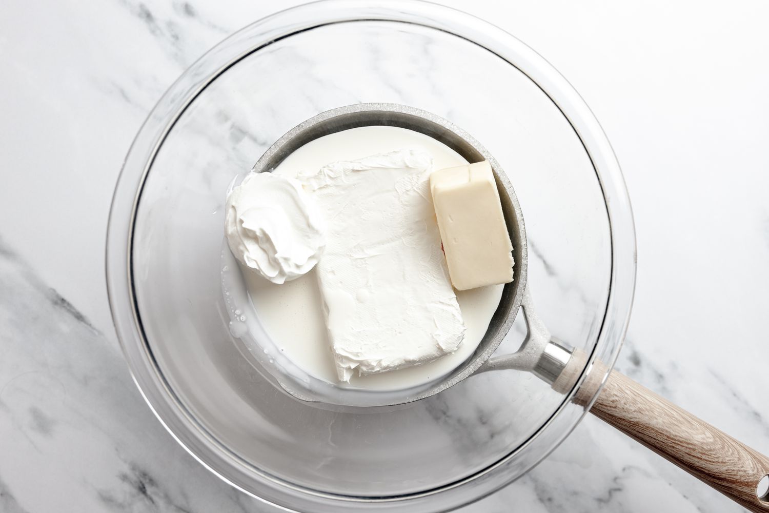Cream, Butter, Sour Cream, and Cream Cheese in a Heat Safe Bowl, Sitting on a Pot of Water (Double Boiler Method) for Japanese Cheesecake