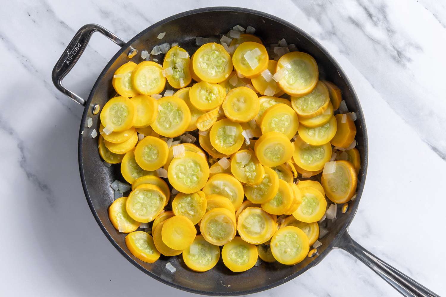 cooked sliced summer squash with onions in a pan for southern squash casserole recipe