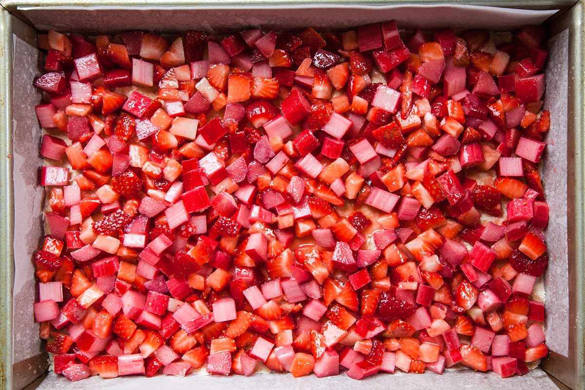 Strawberry Crumble Bars with Rhubarb spread out the ingredients in the pan