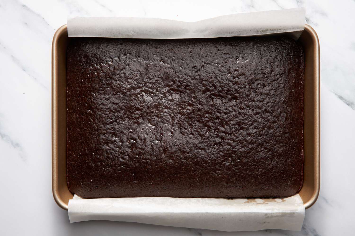 Baked bumpy cake in the parchment paper-lined baking pan