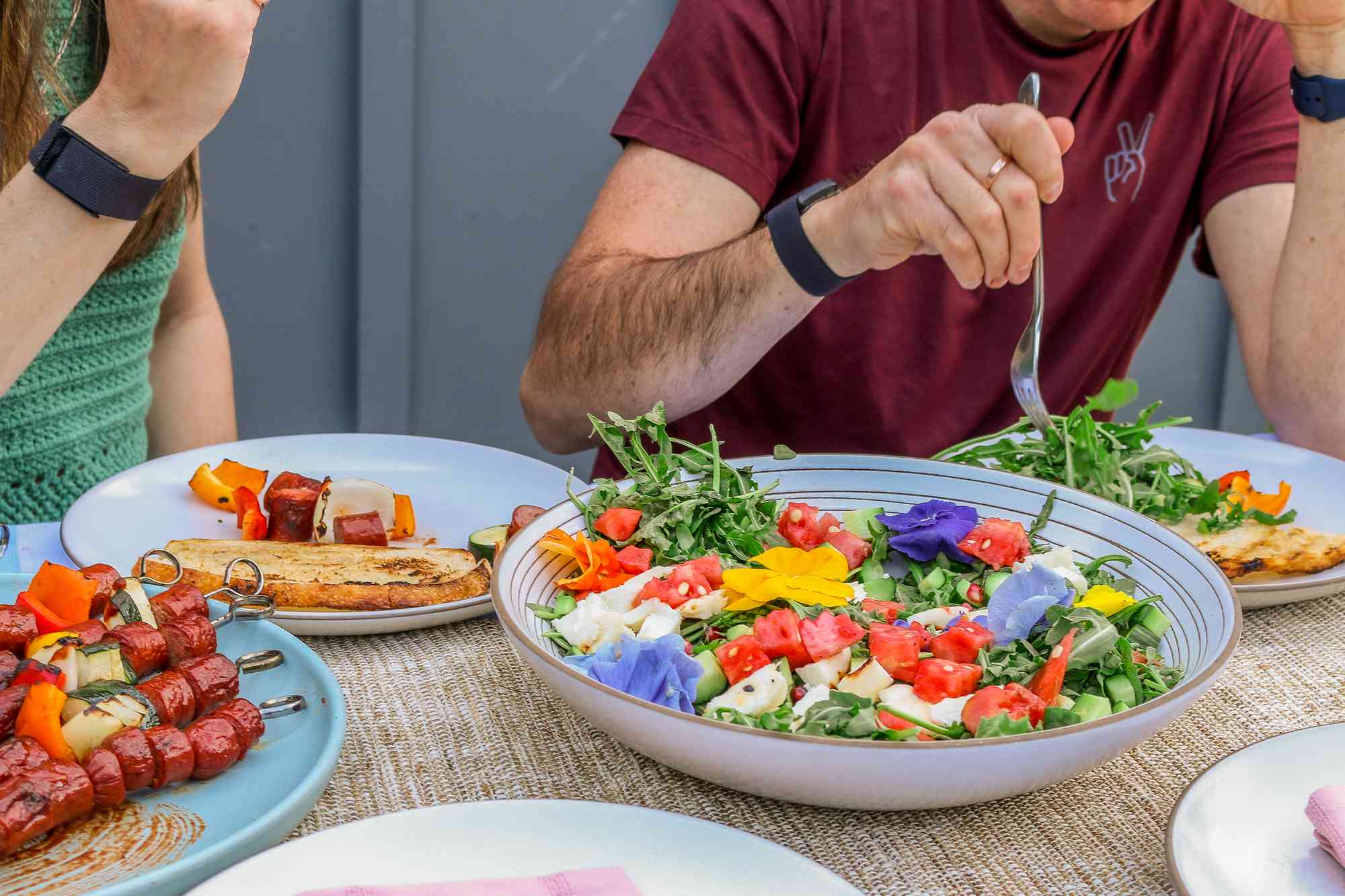 A salad and grilled meat spread on an outdoor table