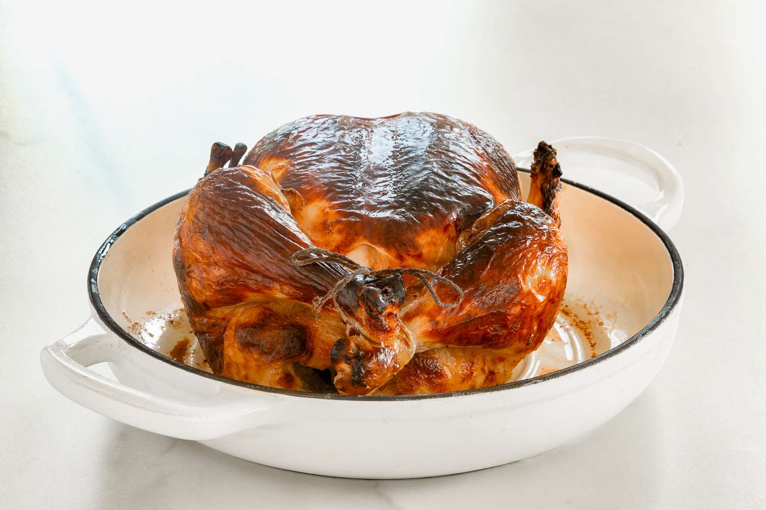 Side view of a roasted chicken in a round baking dish