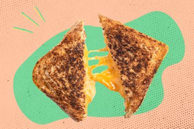 A grilled cheese sandwich cut in half with melted cheese stretching between the halves